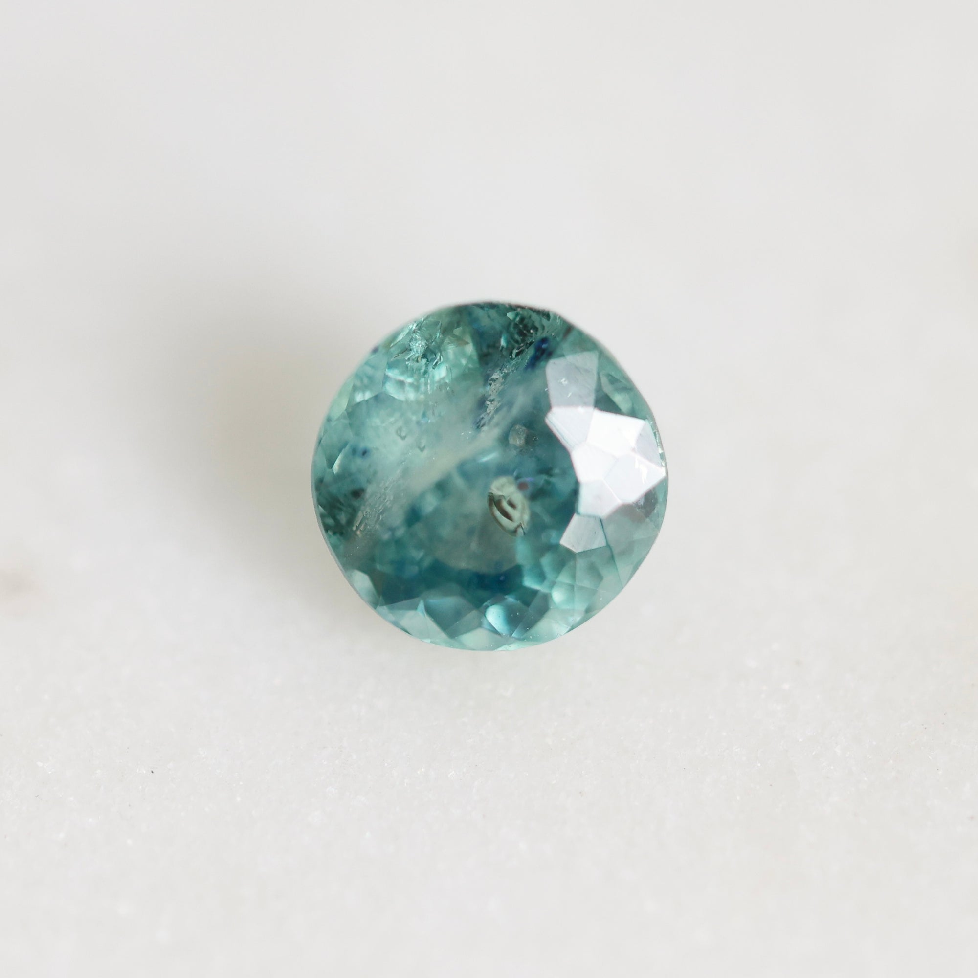 Greenish blue round montana sapphire with swirling inclusions