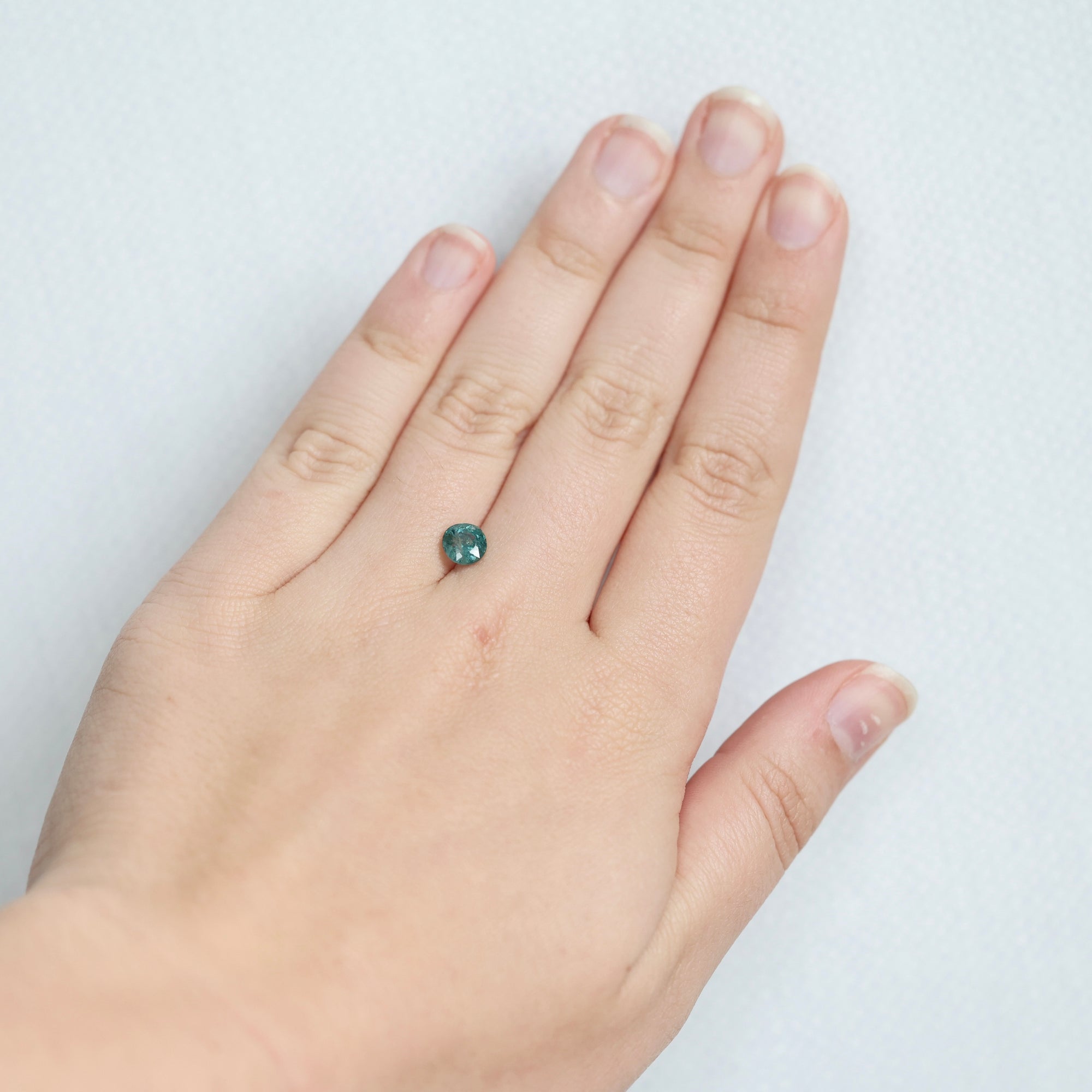 Greenish blue montana sapphire on hand 