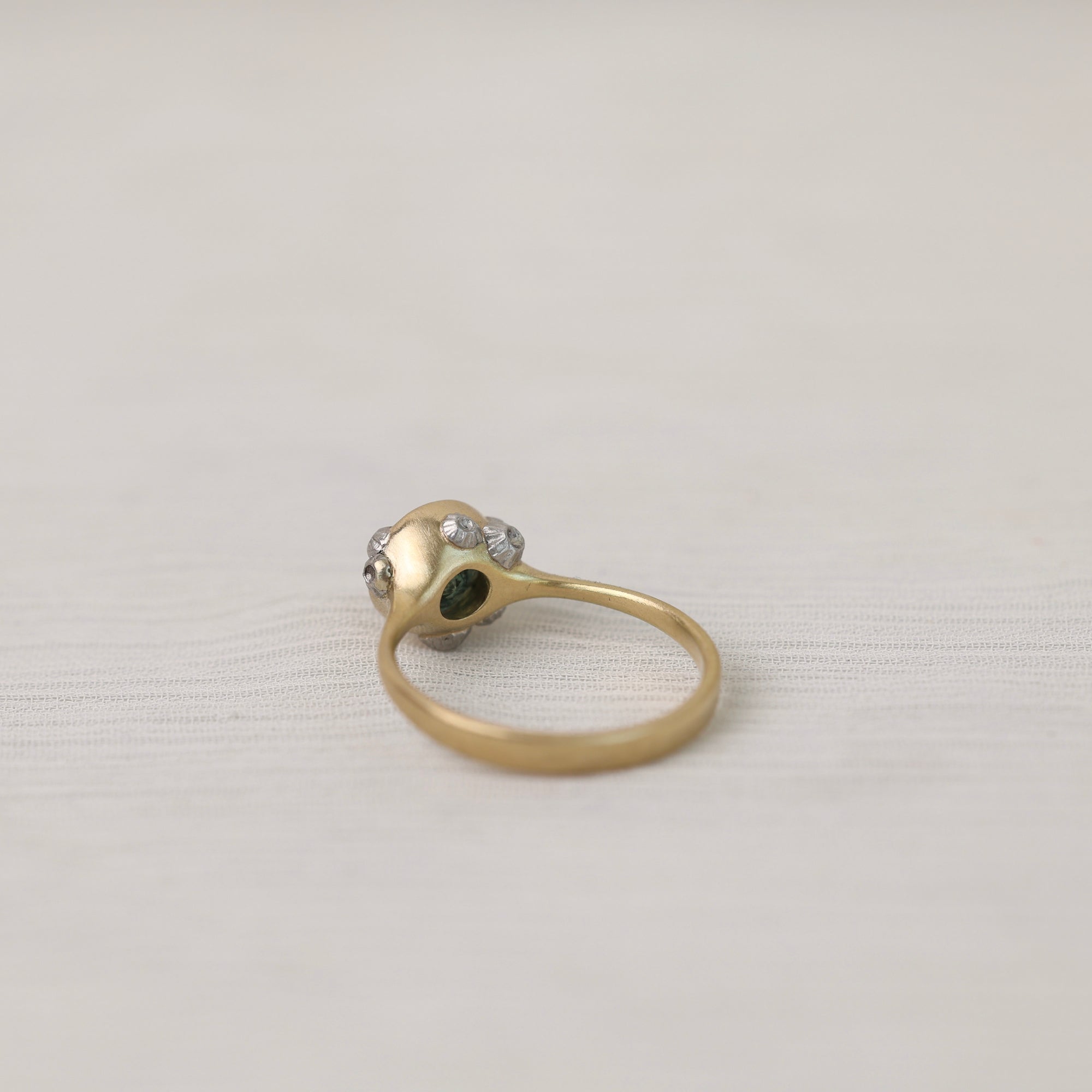 Gold ring with a central gemstone and barnacles on a light gray background