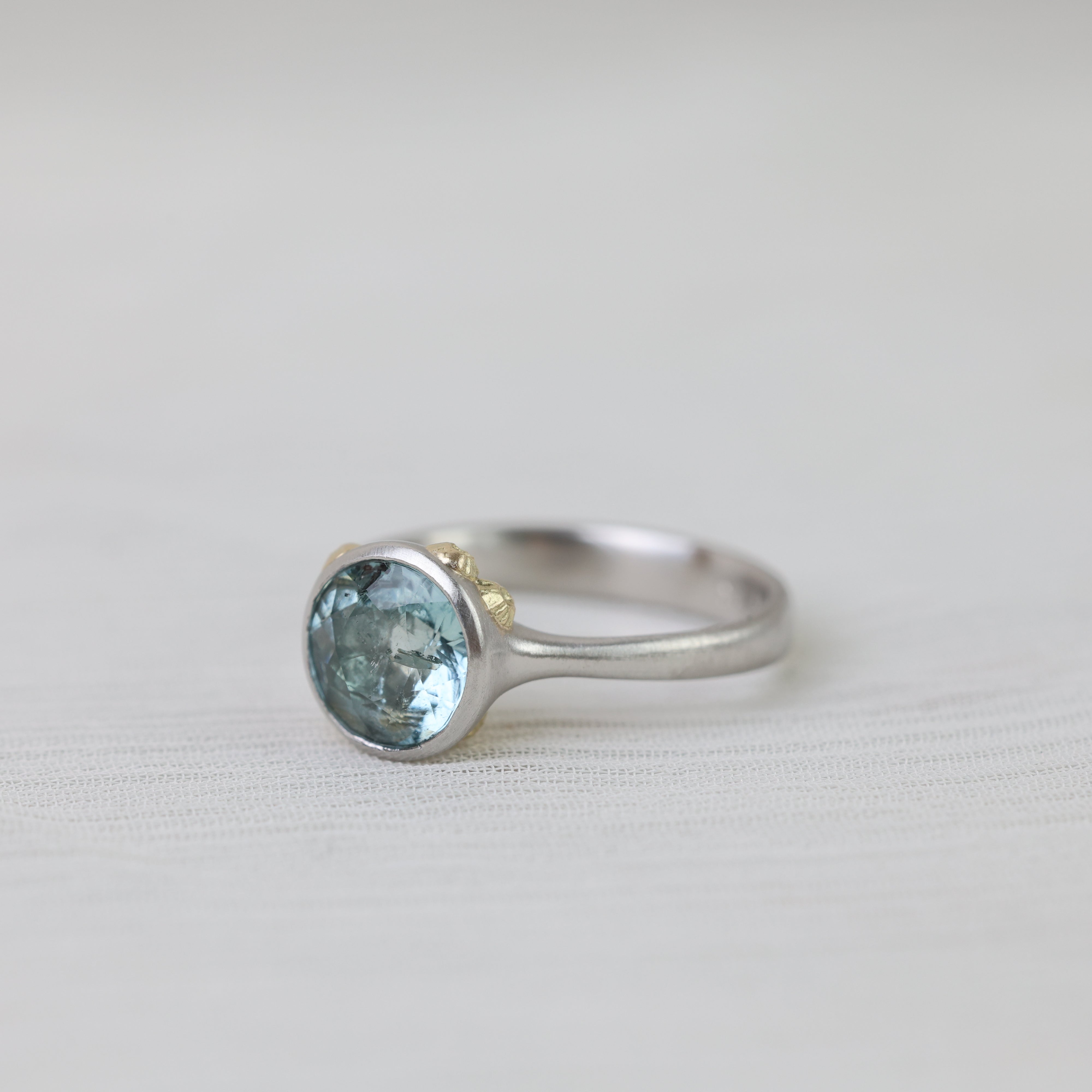 Silver ring with a blue gemstone on a light gray background