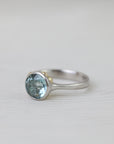 Silver ring with a blue gemstone on a light gray background