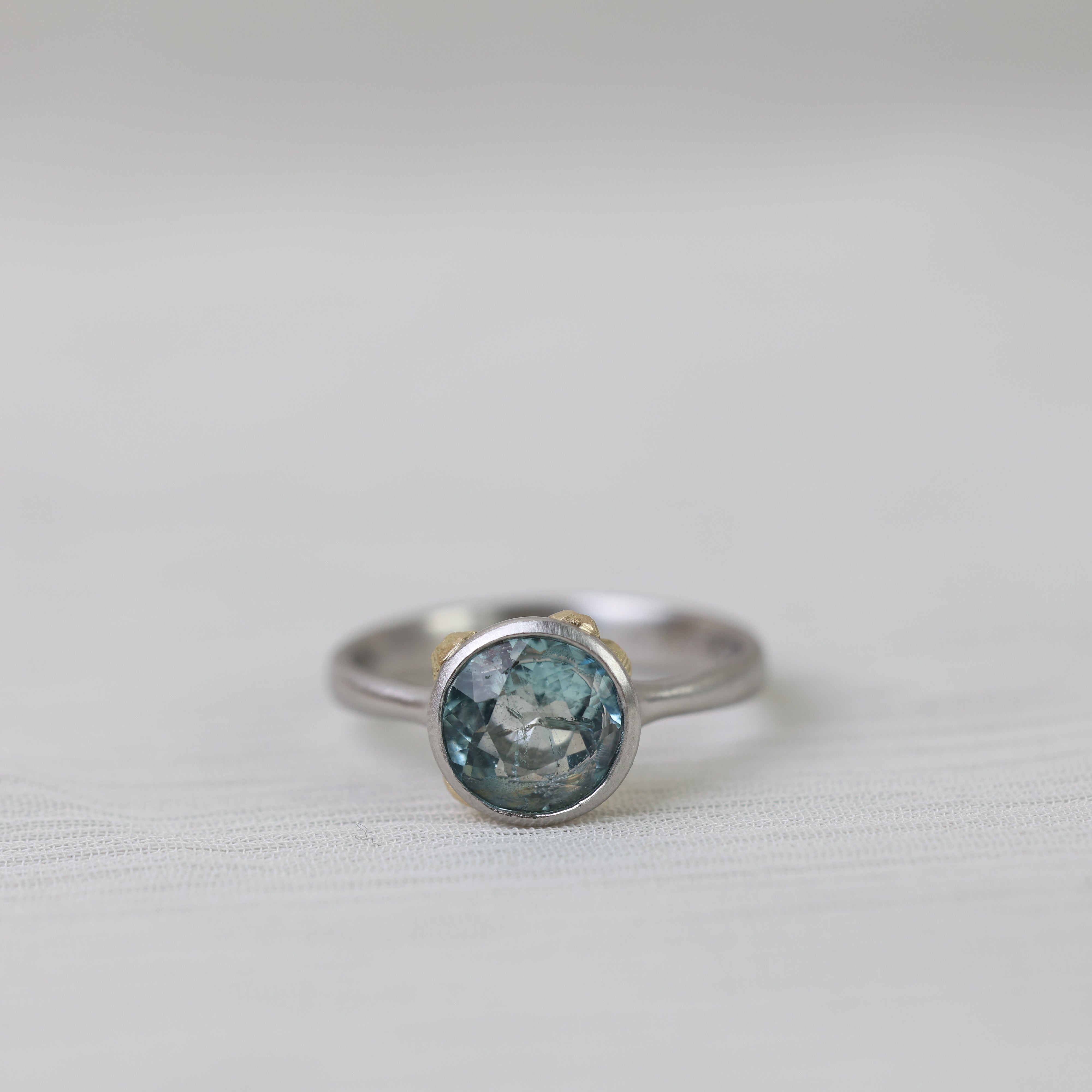 Silver ring with a blue gemstone on a light gray background
