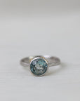 Silver ring with a blue gemstone on a light gray background