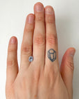 Hand with a stone ring on a finger and a small tattoo on another finger against a white background
