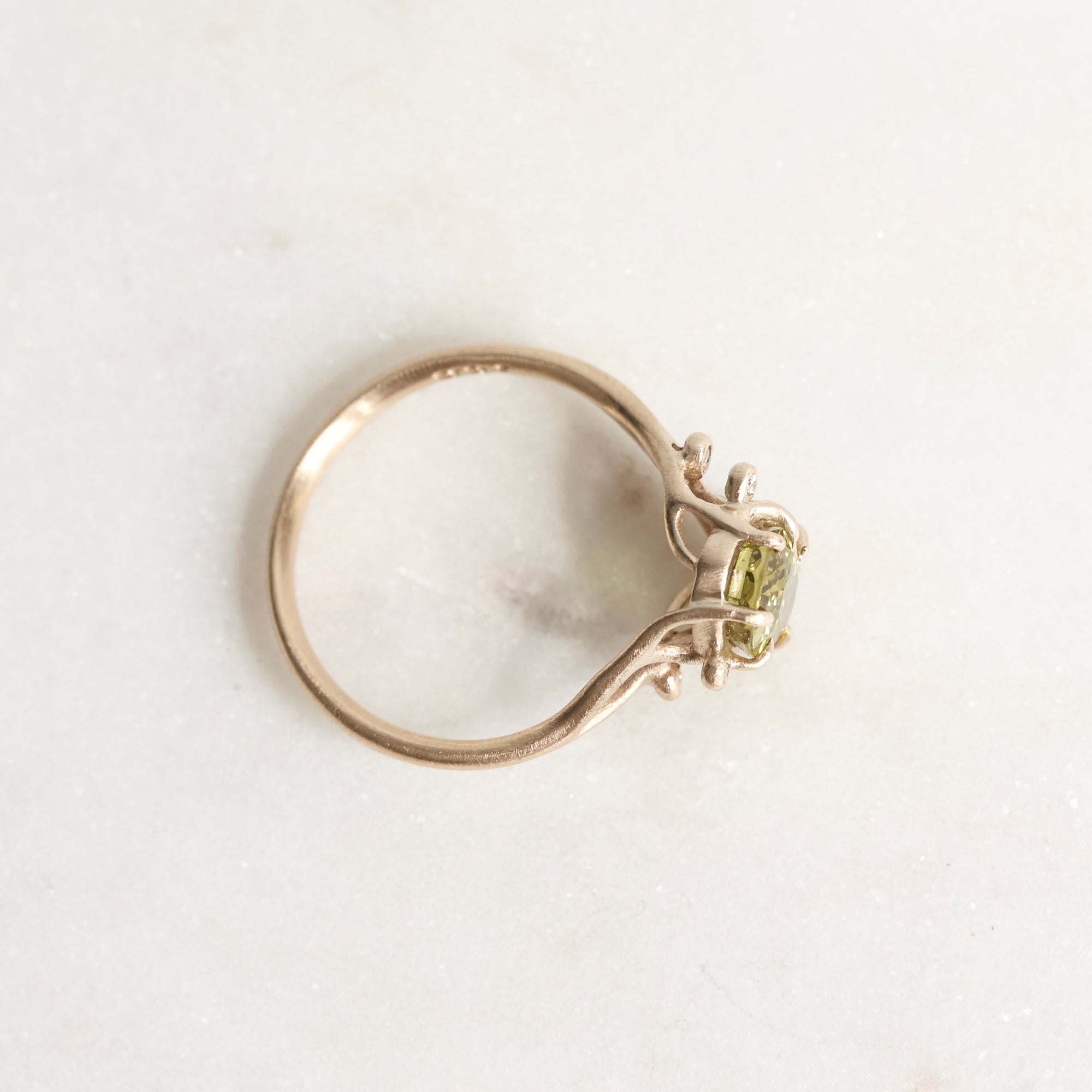 Gold ring with a green gemstone on a light gray background