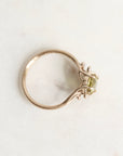 Gold ring with a green gemstone on a light gray background
