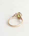 Gold ring with a green gemstone on a light gray background