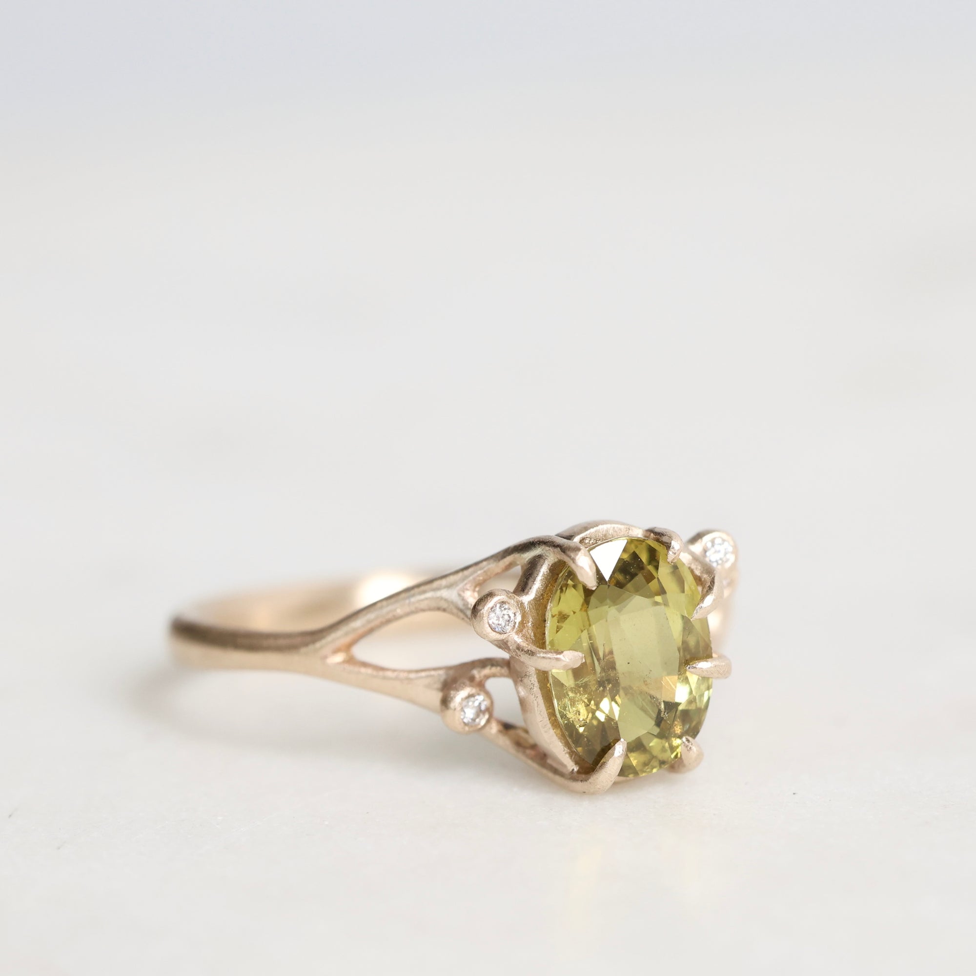 Gold ring with a green gemstone on a light gray background