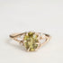 Gold ring with a green gemstone and small diamonds on a light gray background