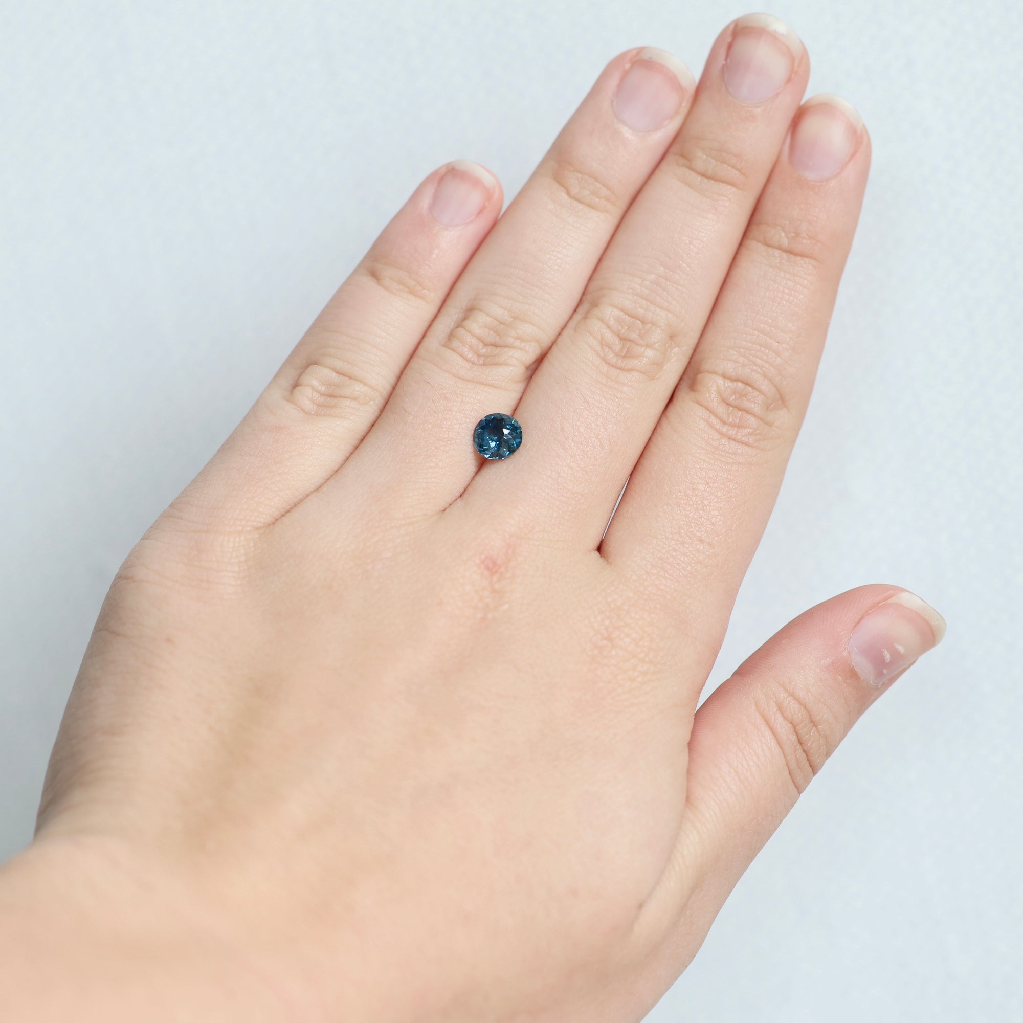 Round bright blue montana sapphire on hand 