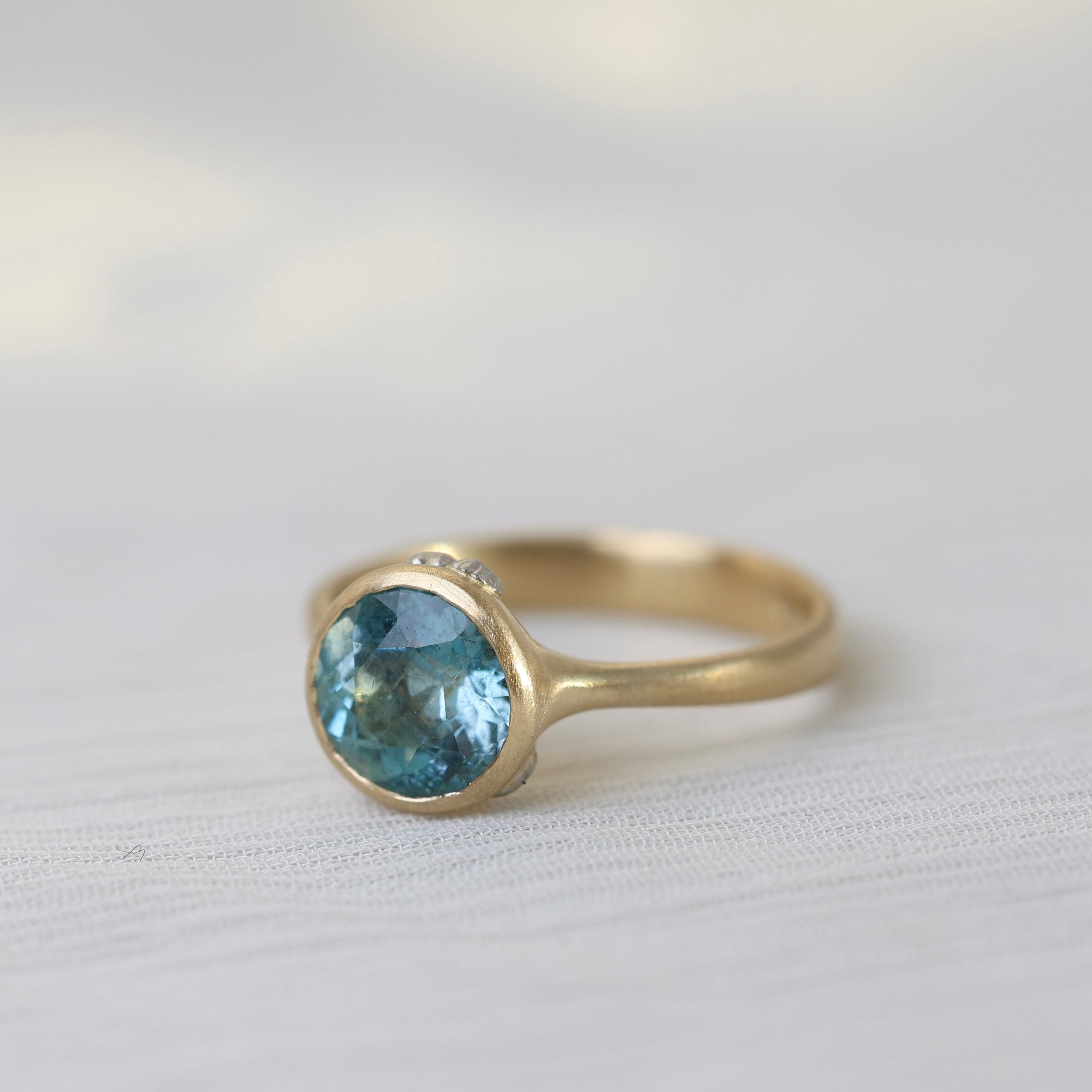 Gold ring with a blue gemstone on a light fabric background