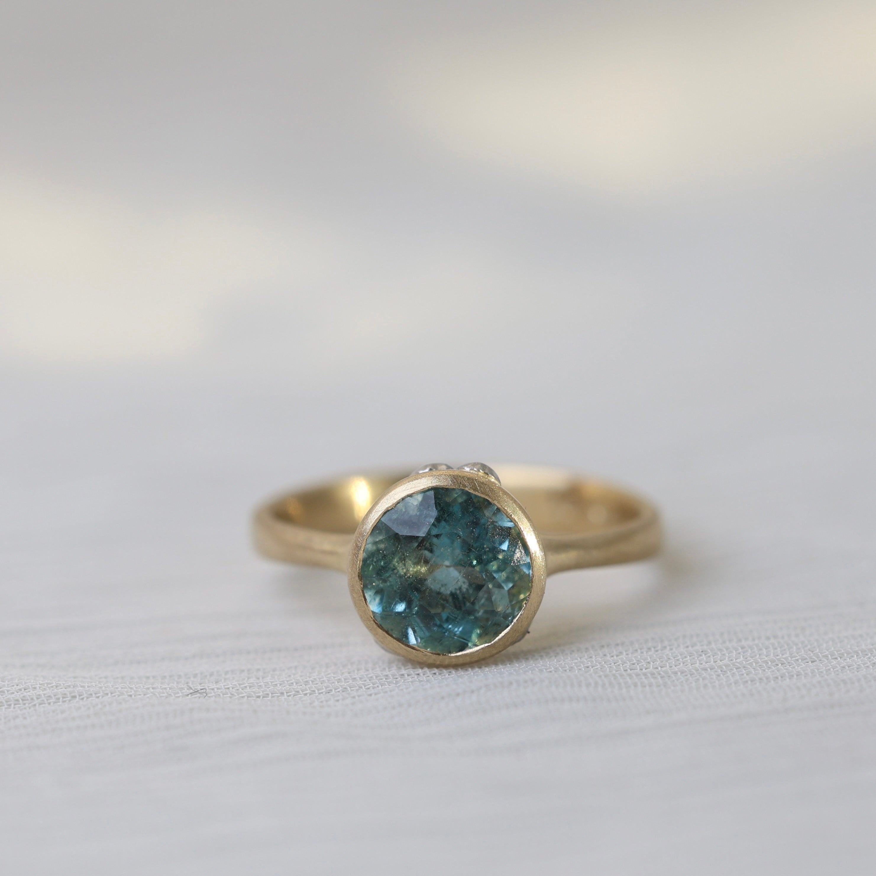 Gold ring with a blue gemstone on a white fabric background