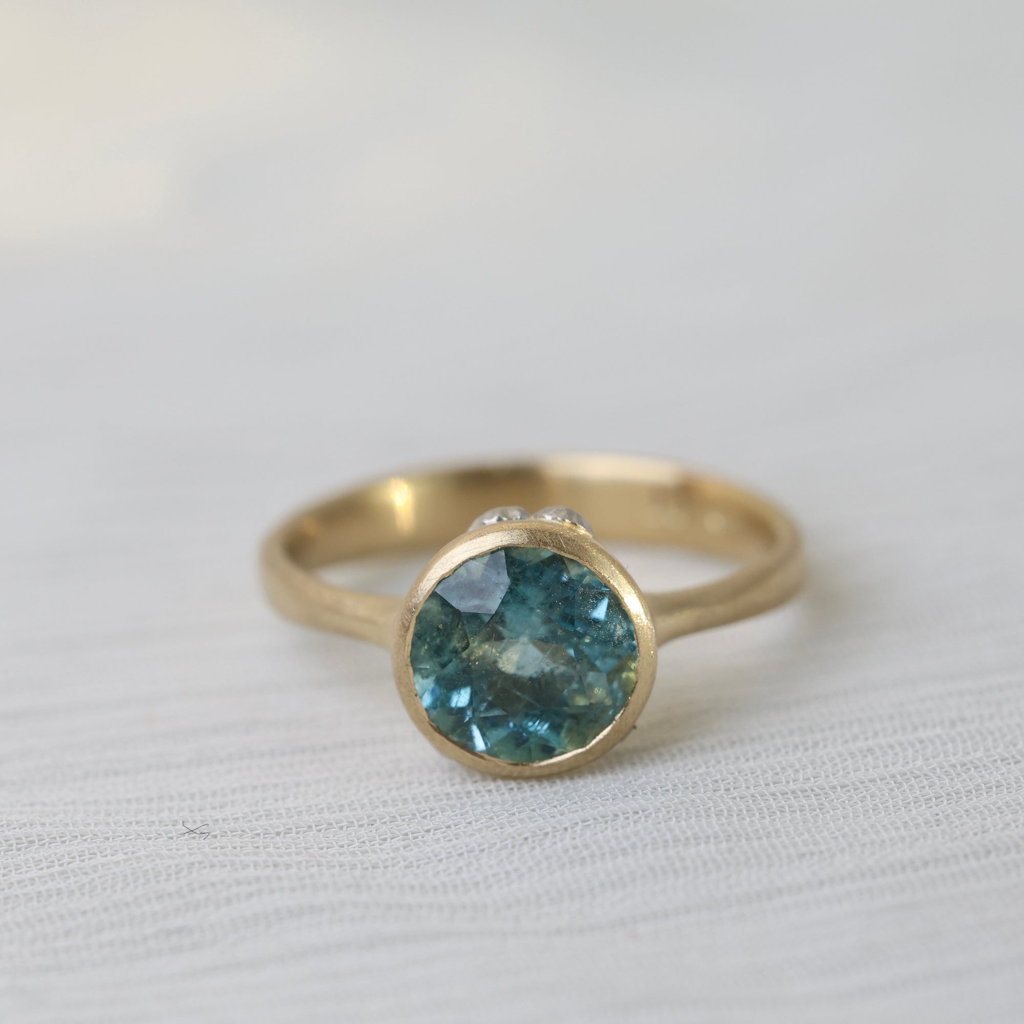 Gold ring with a blue gemstone on a white fabric background