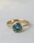Gold ring with a blue gemstone on a white fabric background