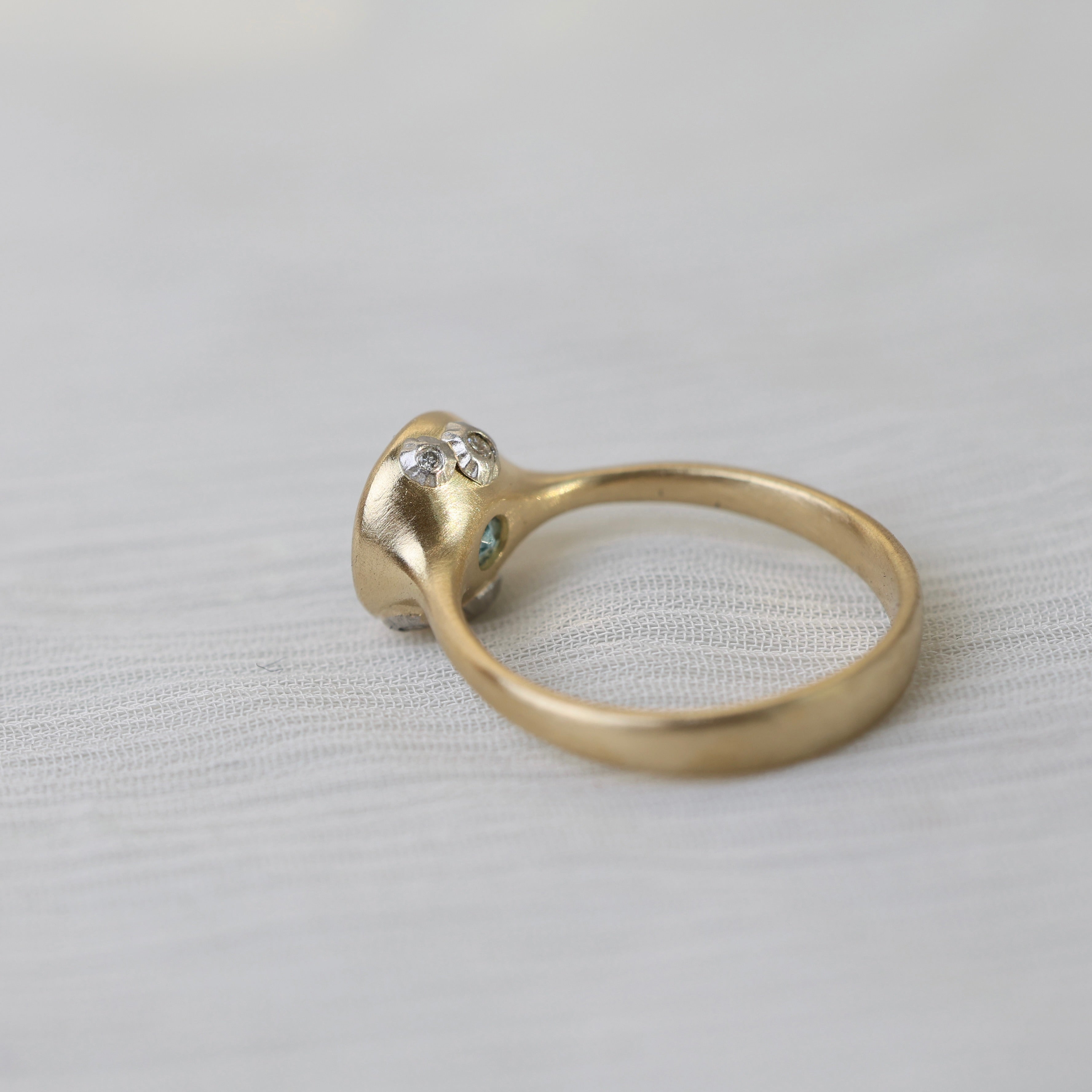 Gold ring with gemstones on a light fabric background