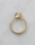 Gold ring with a central gemstone and smaller diamonds on a light fabric background