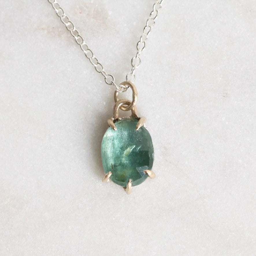 Necklace with a green gemstone pendant on a light background