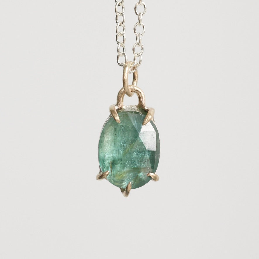 Necklace with a green gemstone pendant on a light gray background