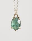 Necklace with a green gemstone pendant on a light gray background