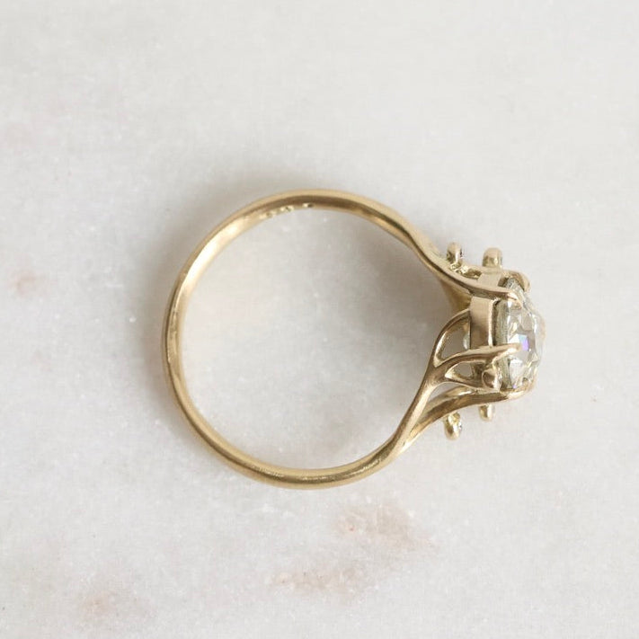 Gold ring with a diamond on a light marble background