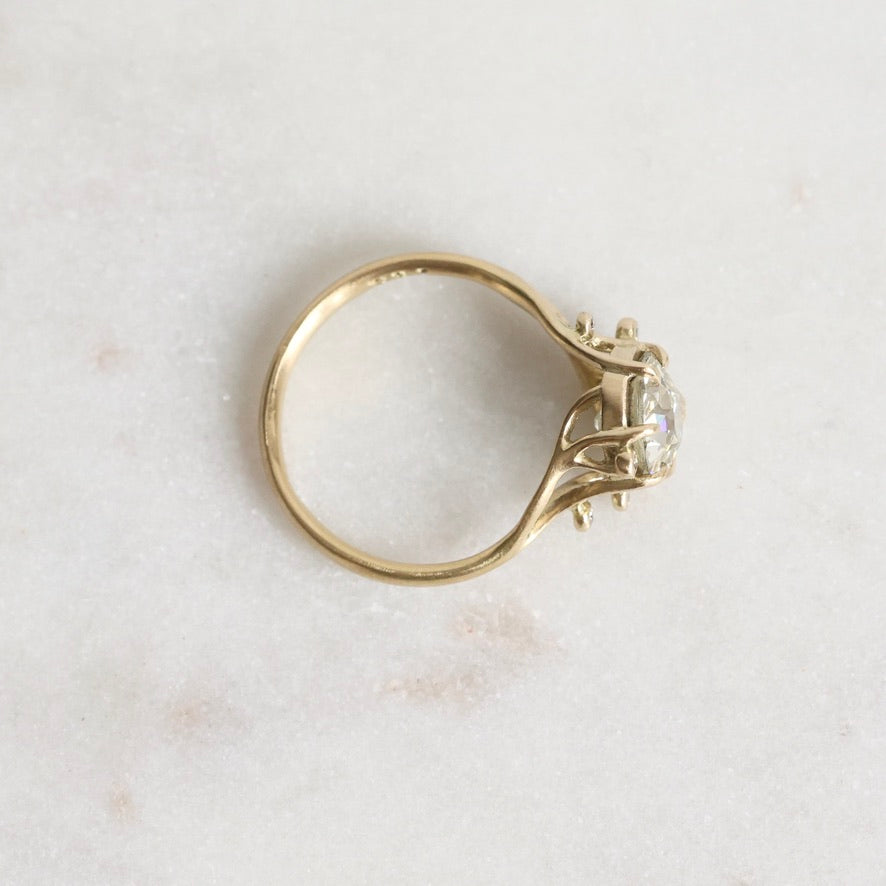 Gold ring with a diamond on a light marble background