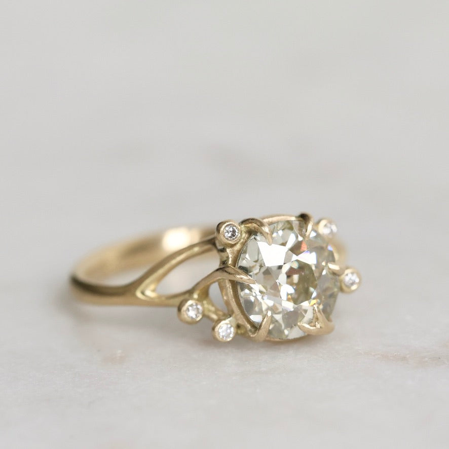 Gold ring with a large diamond and smaller stones on a light gray background
