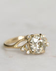 Gold ring with a large diamond and smaller stones on a light gray background