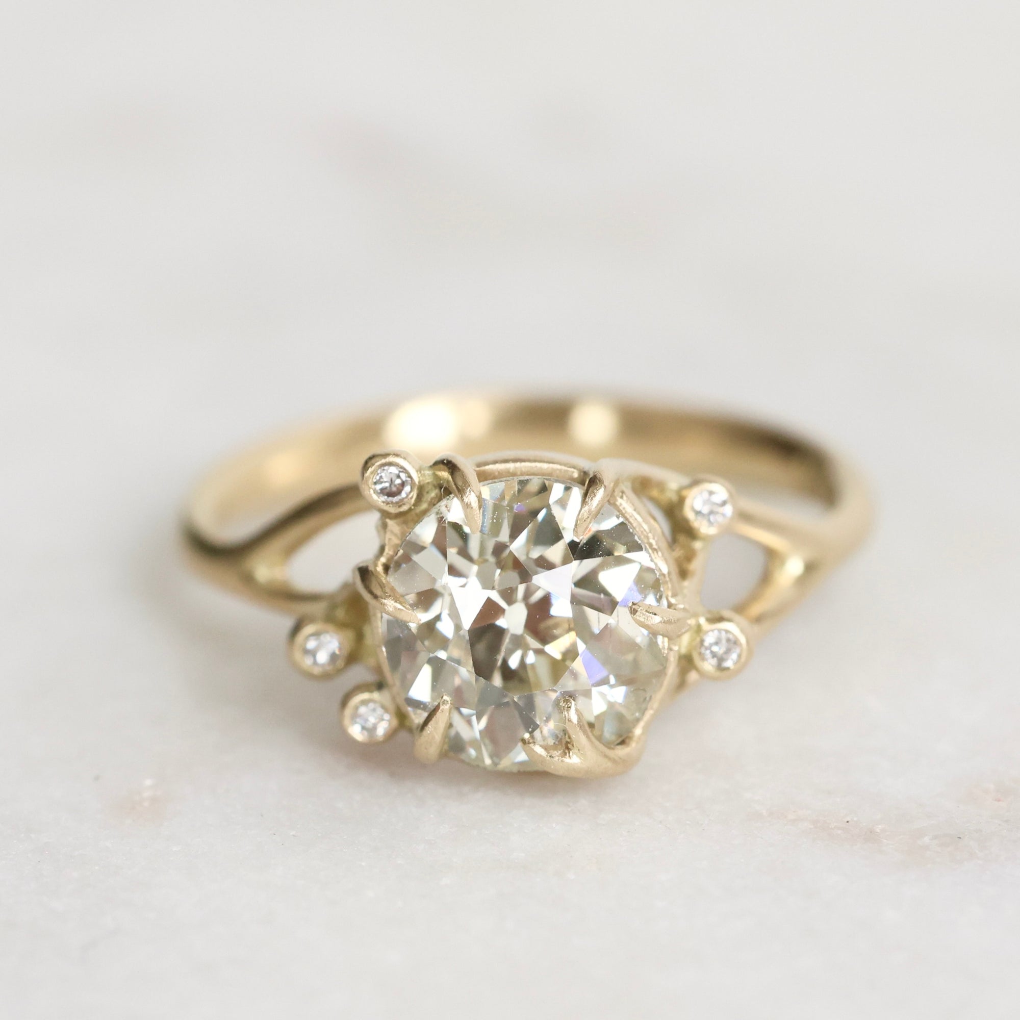 Gold ring with a large diamond and smaller diamonds on a light background