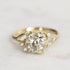 Gold ring with a large diamond and smaller diamonds on a light background