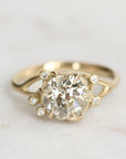 Gold ring with a large diamond and smaller diamonds on a light background
