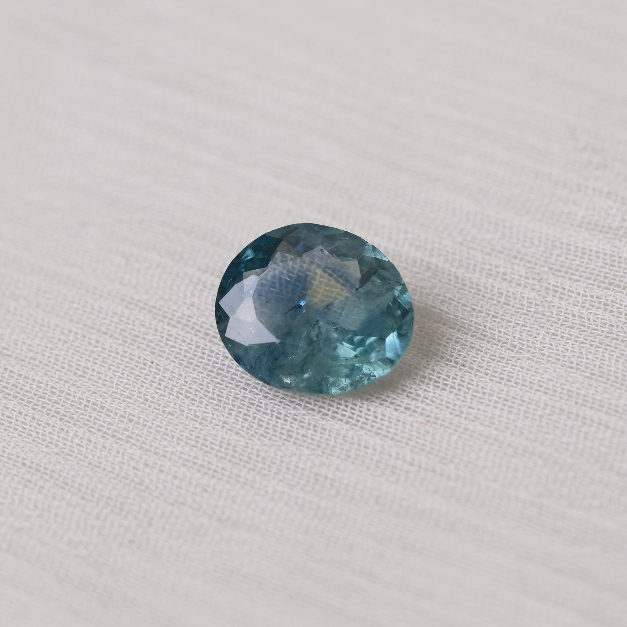 Faceted blue gemstone on a light fabric background