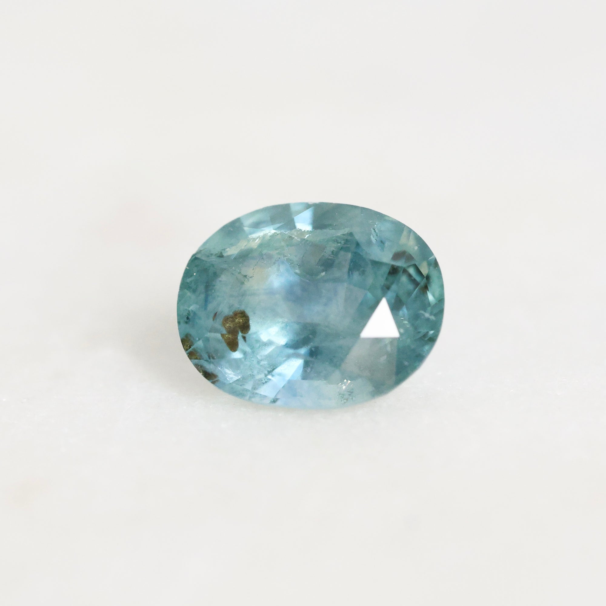 Blue sapphire with inclusion on a white background