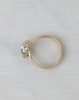 Gold ring with a central gemstone and smaller stones on a light gray background