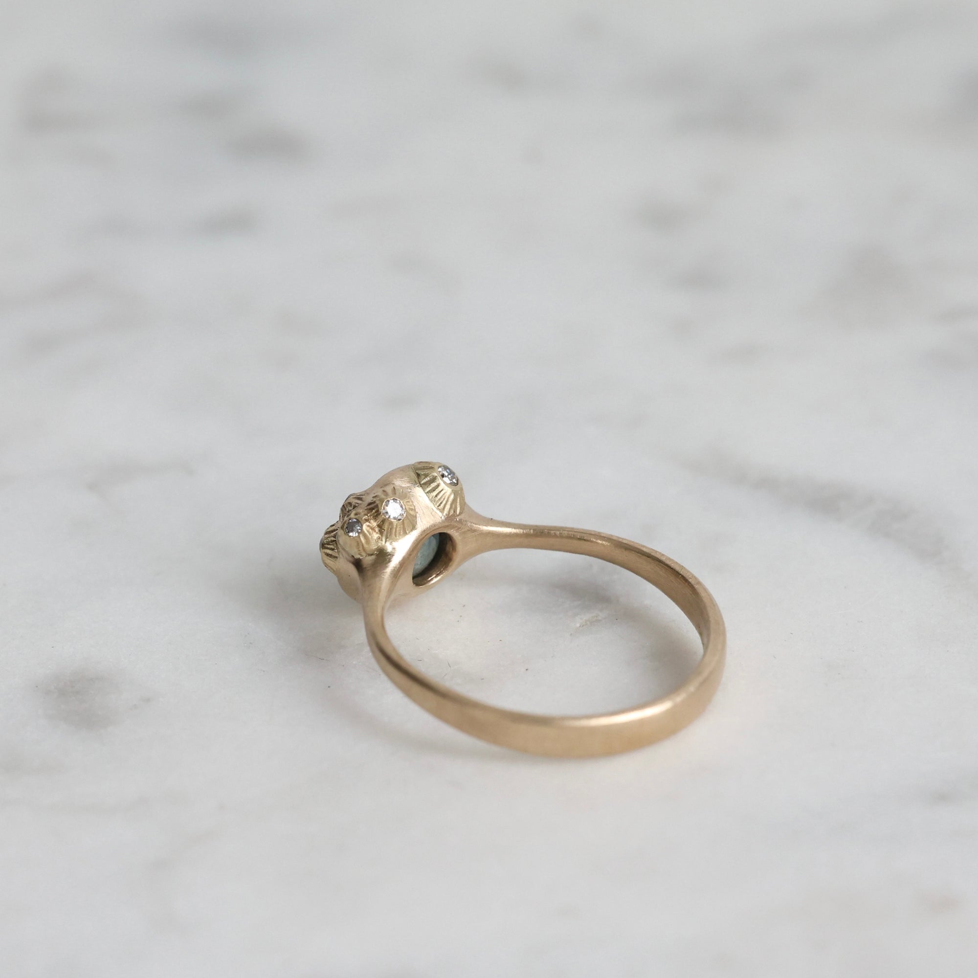 Gold ring with a diamond on a marble surface