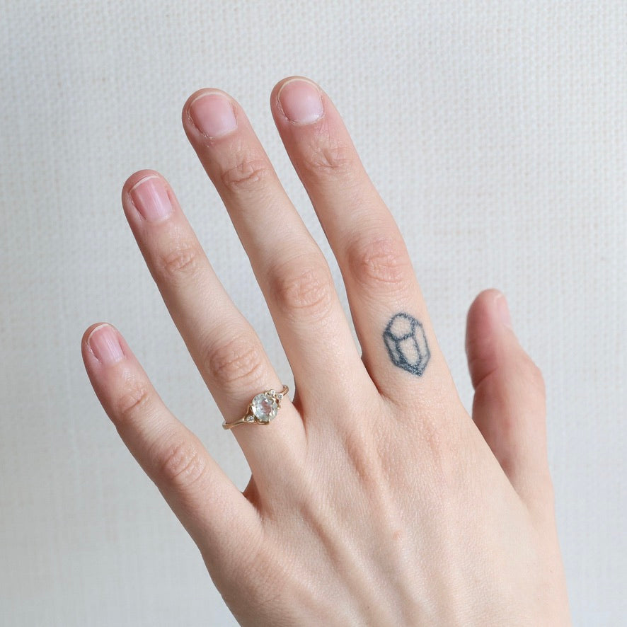 Hand with a ring and a small tattoo on a plain background