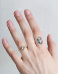 Hand with a ring and a small tattoo on a plain background