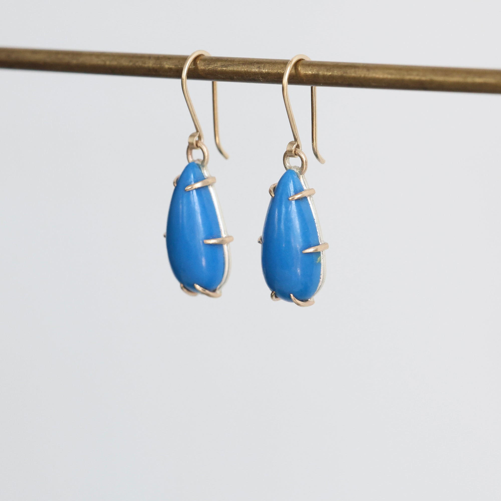 Blue teardrop earrings with gold accents on a white background