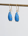 Blue teardrop earrings with gold accents on a white background