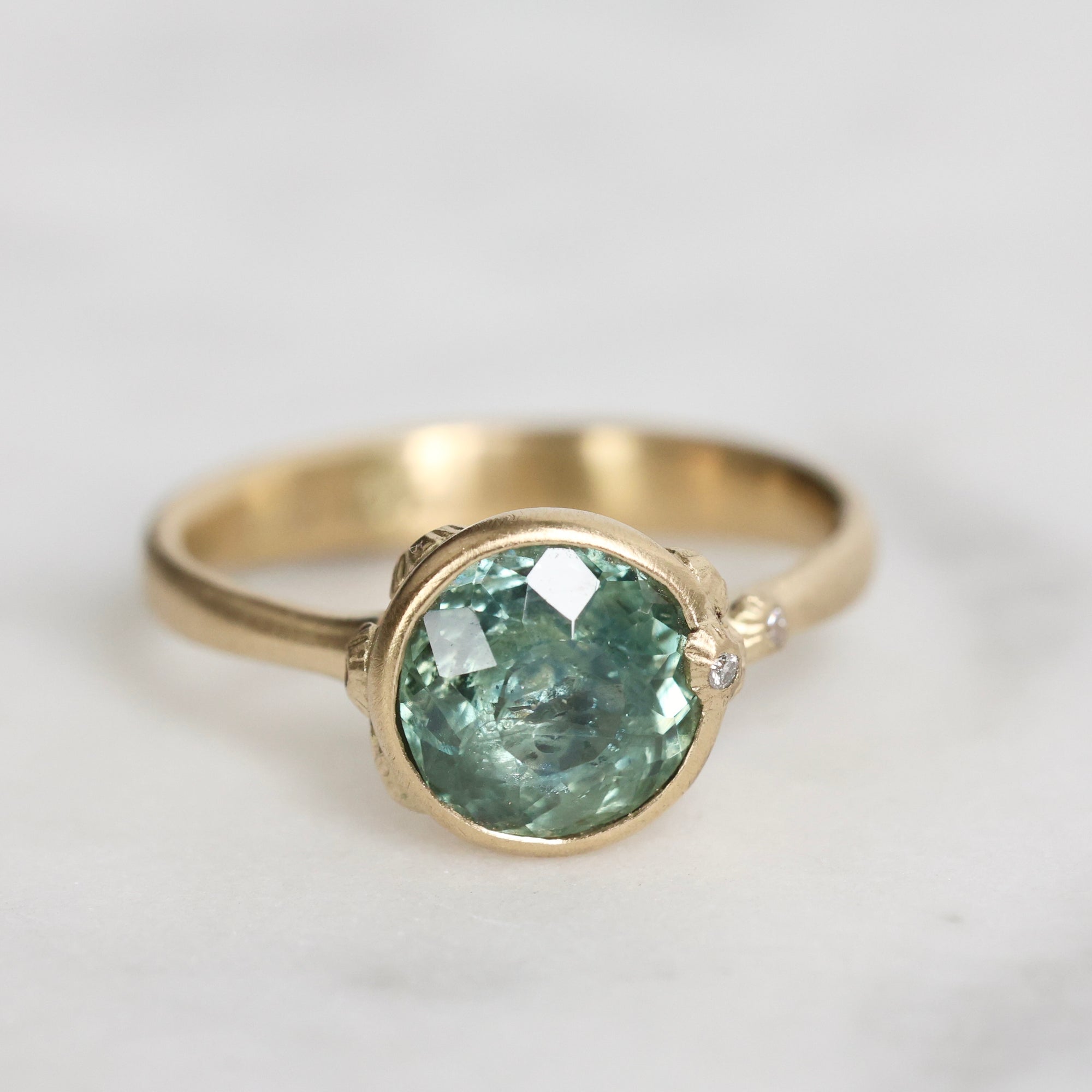 Gold ring with a green gemstone on a light gray background