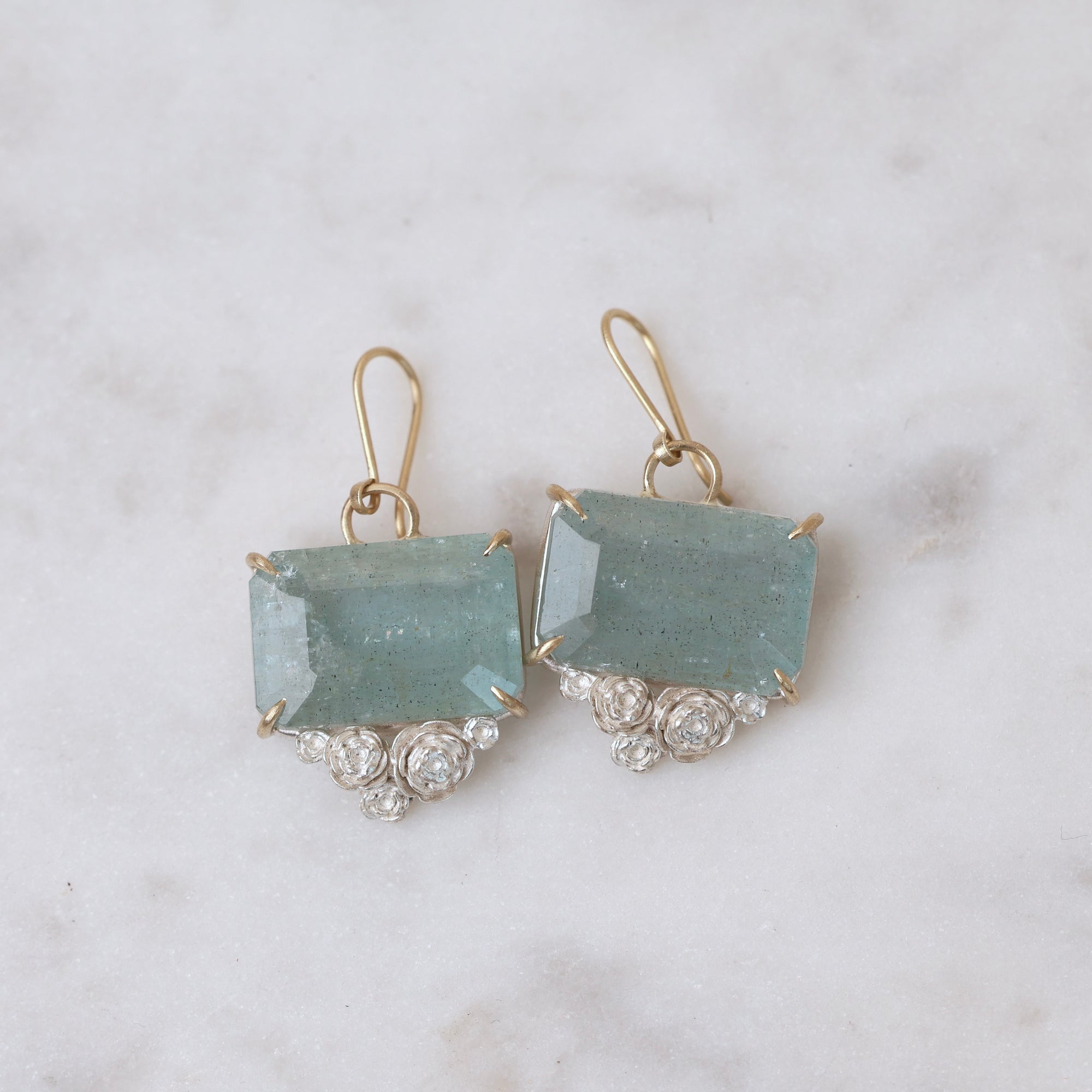Pair of earrings with blue gemstones and gold accents on a marble background