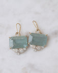 Pair of earrings with blue gemstones and gold accents on a marble background