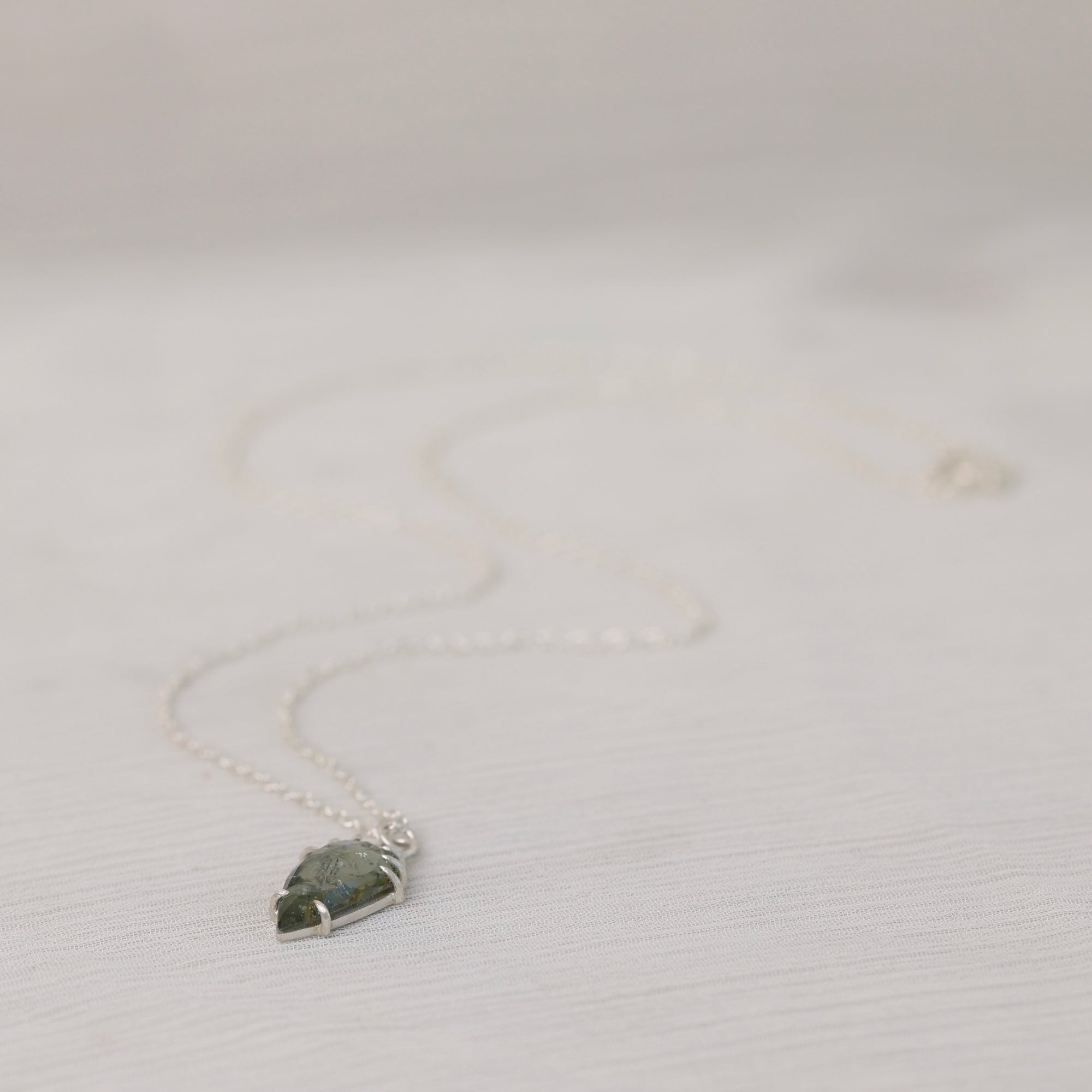 Necklace with a green stone pendant on a light gray background