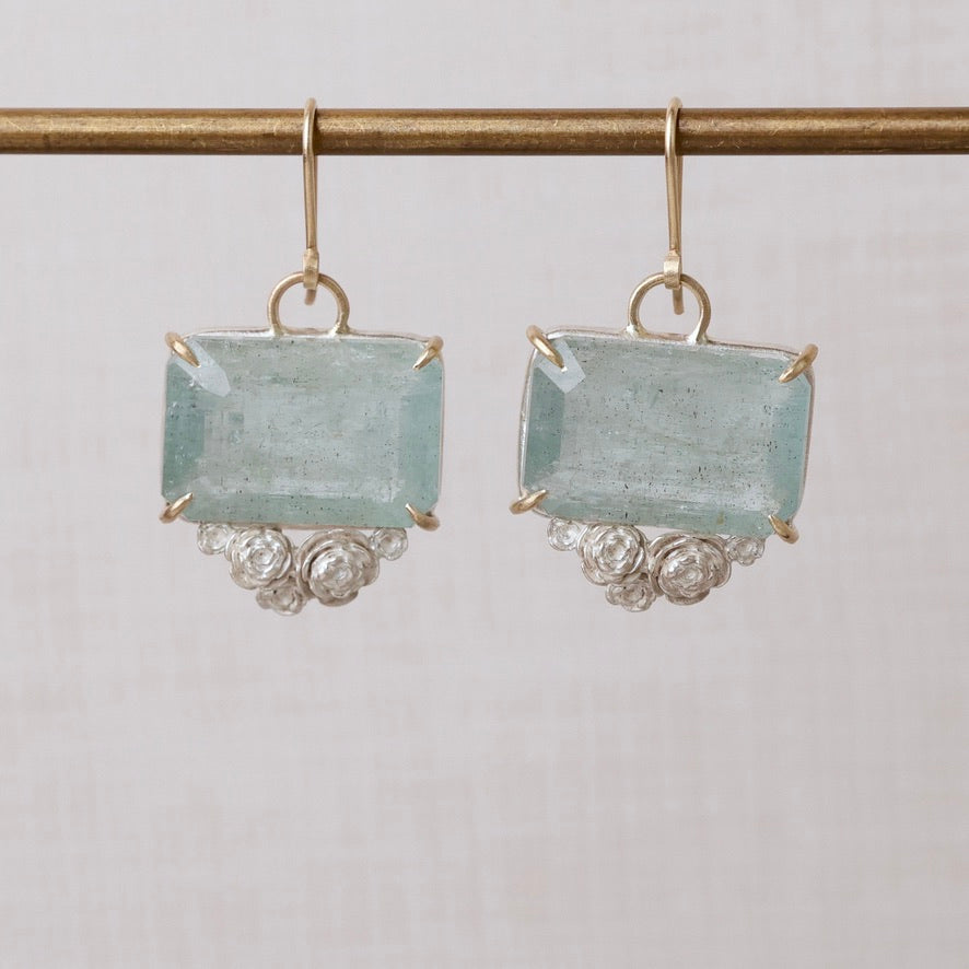 Pair of earrings with rectangular gemstones on a light gray background