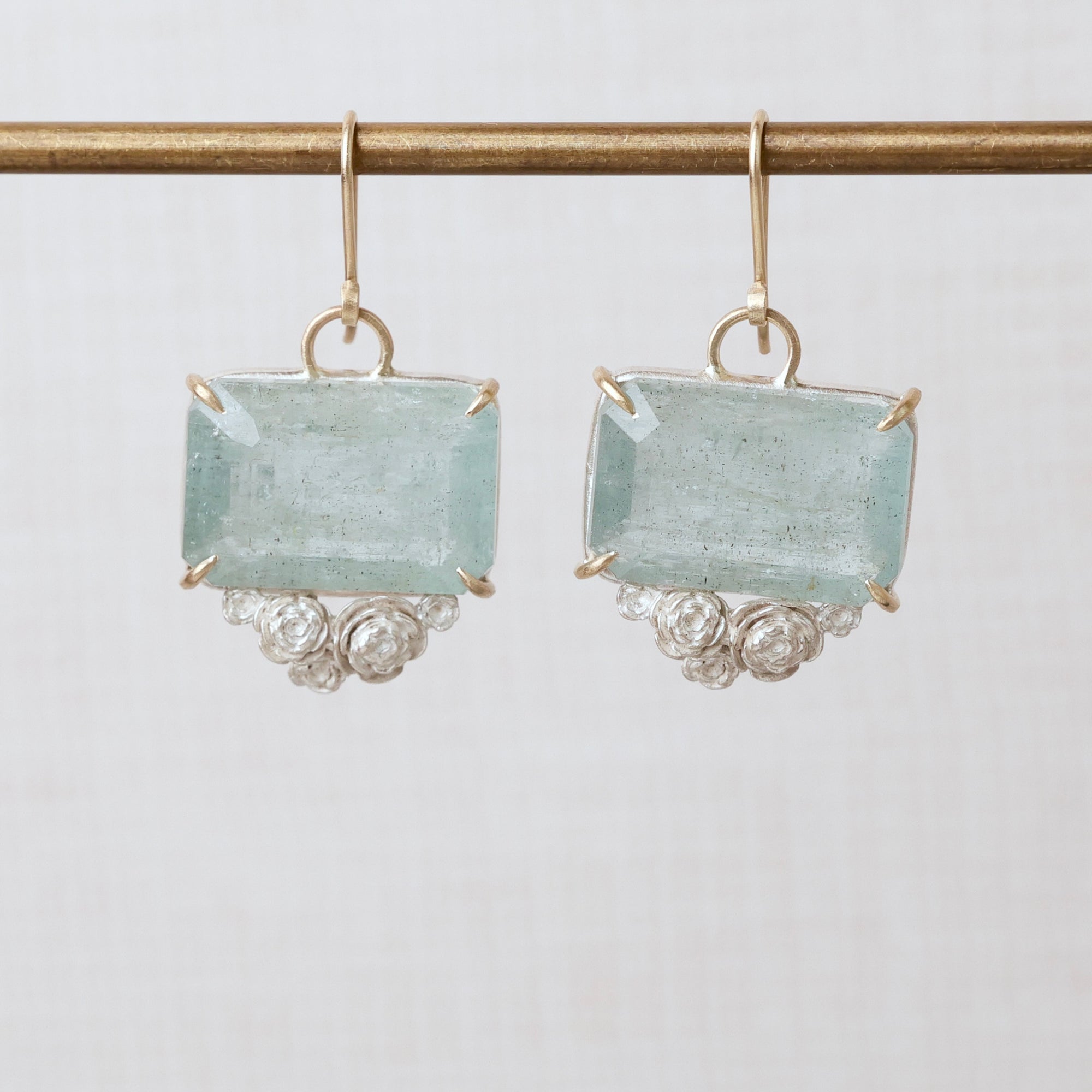 Aquamarine earrings with gold and silver accents on a light gray background