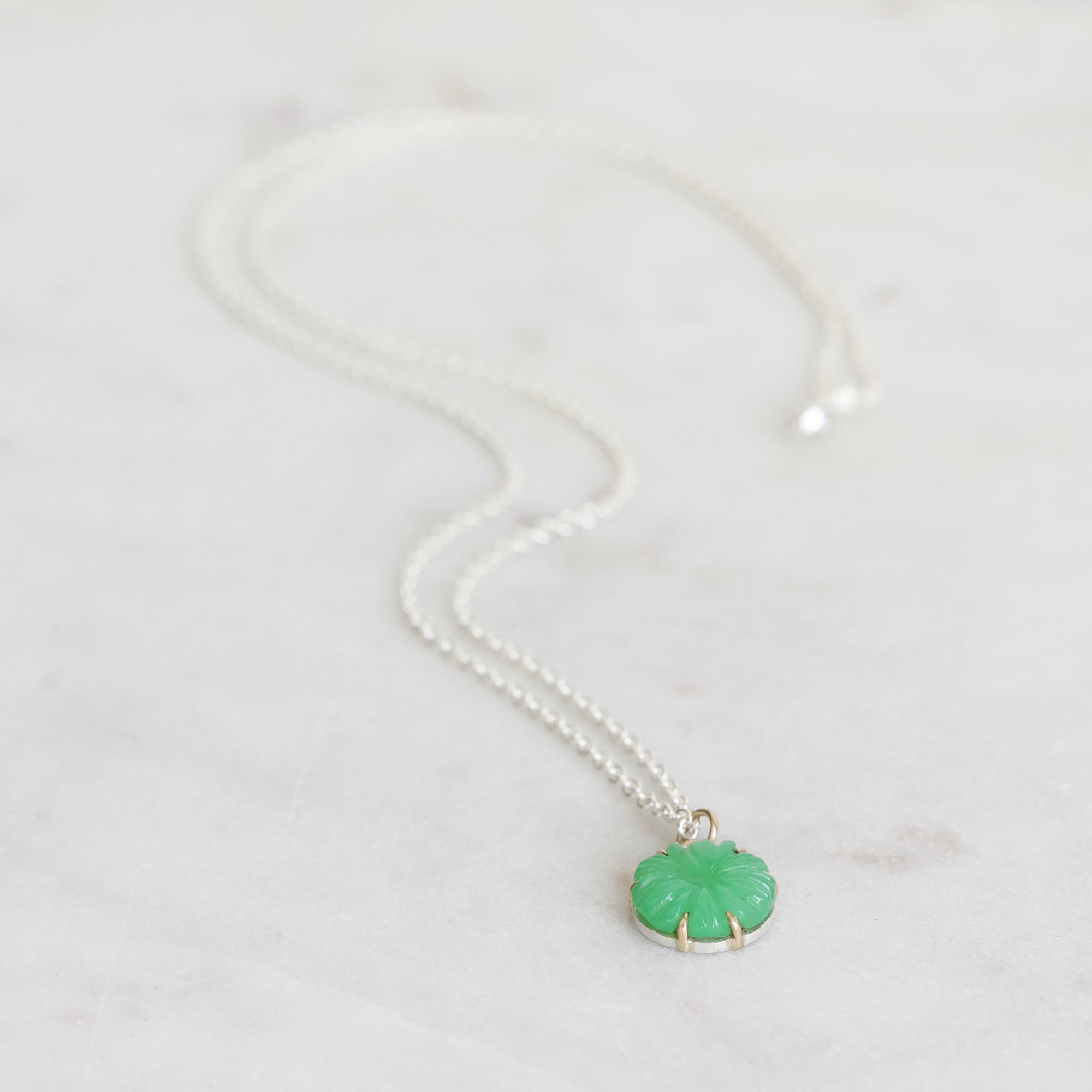 Necklace with a green pendant on a light gray background