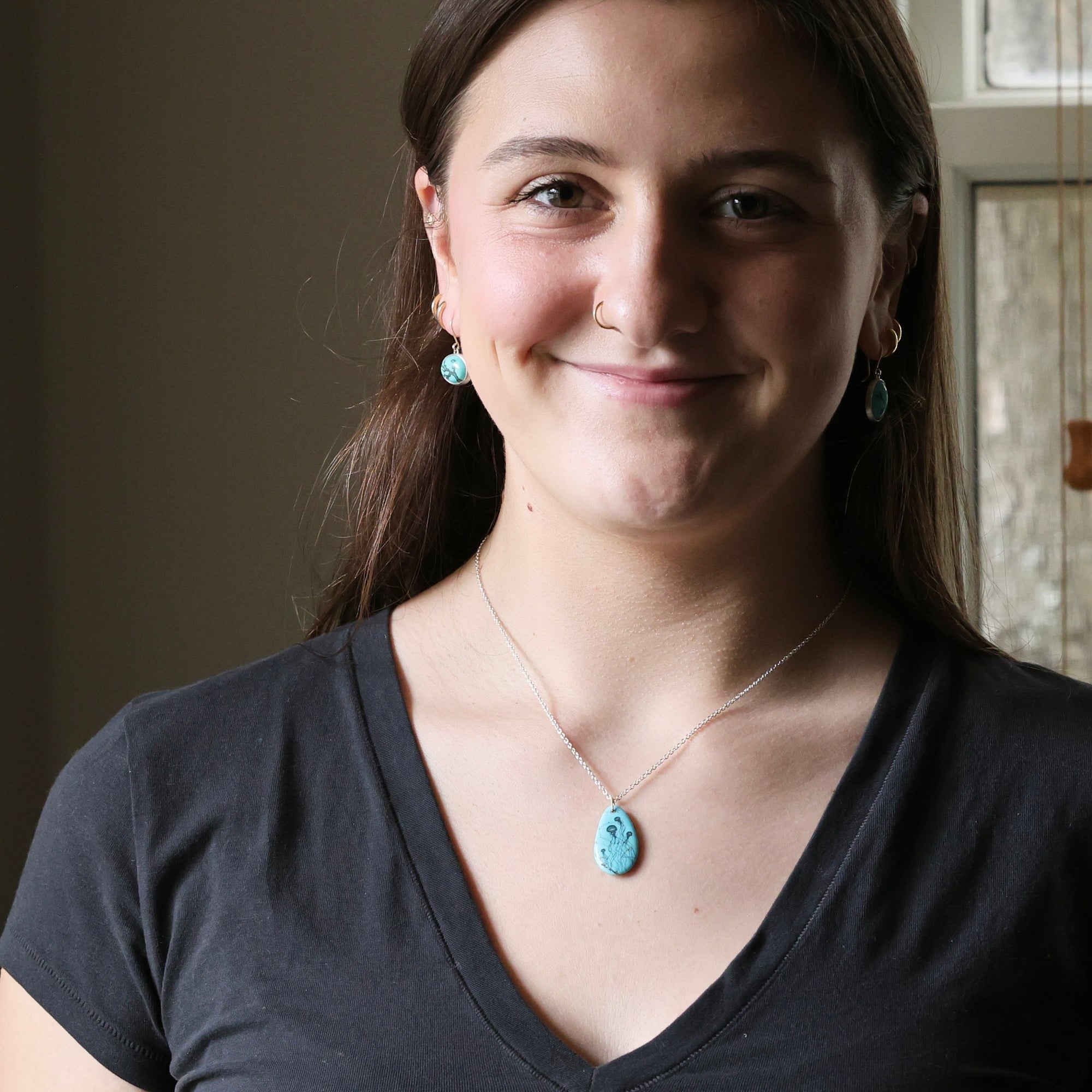 Woman wearing a necklace with a blue pendant indoors