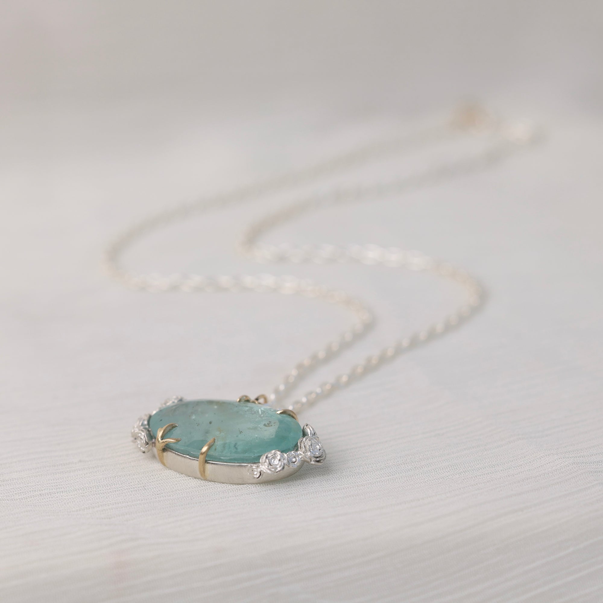 Necklace with a pendant featuring a green stone and small roses on a light gray background