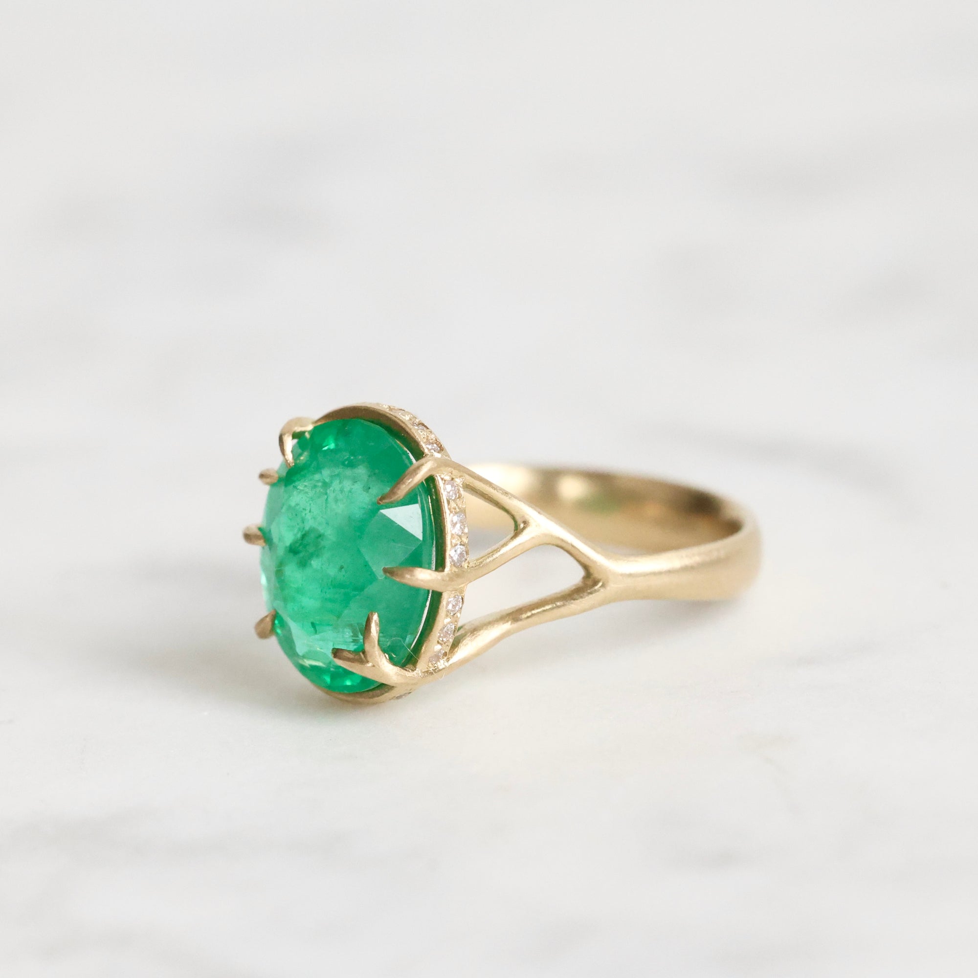 Large green gemstone ring with a diamond halo and branchy setting