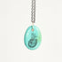 Necklace with a turquoise pendant featuring a black engraved design on a white background