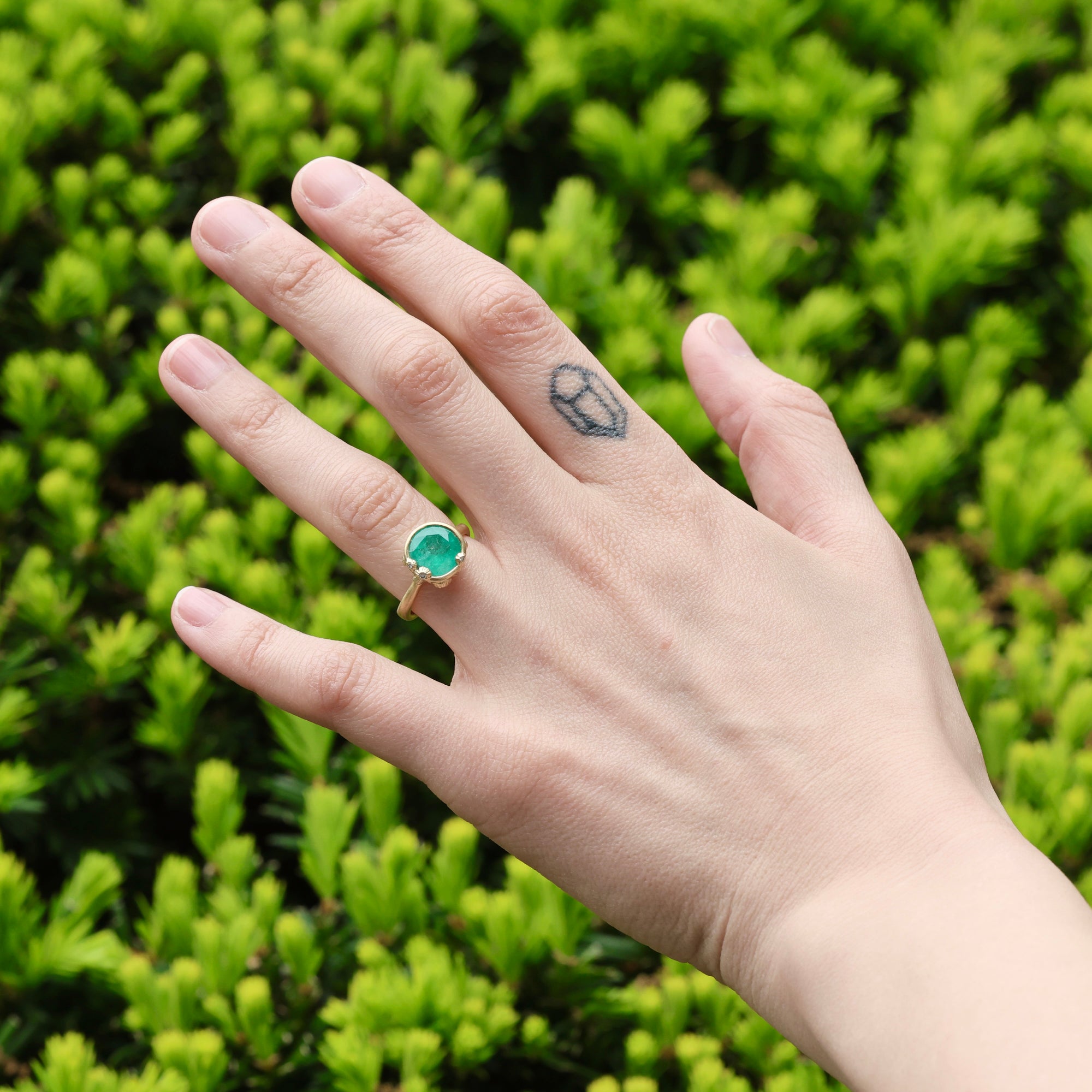Large green gemstone ring on hand with tattoo 